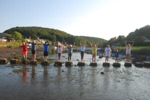 young people standing on stones across the river in Lerryn