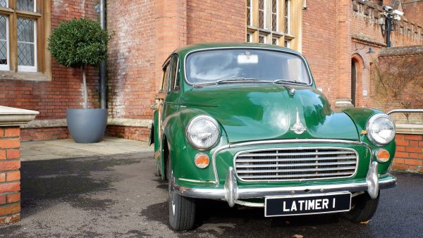 green morris minor car parked beside brown brick building