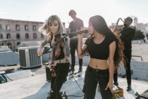 woman in black top singing beside woman playing violin