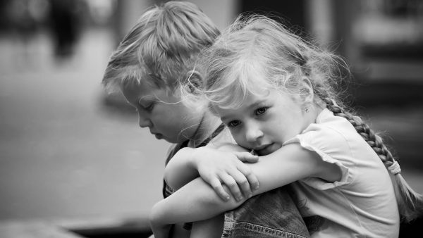 little sad girl with boy using smartphone